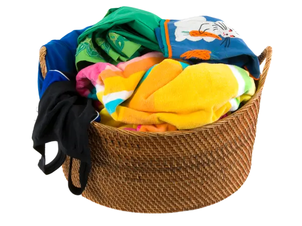 Brown wicker basket filled with laundry, including bright-colored towels and swimsuits.