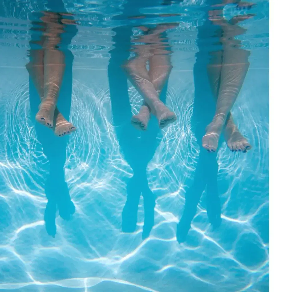 three kids sit next to each other in this underwater pool shot.