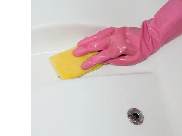 Hand in pink glove wiping down hot tub surface with a yellow rag