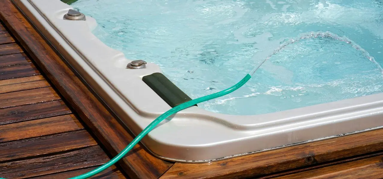In-ground swim spa with a hose over it refilling it.