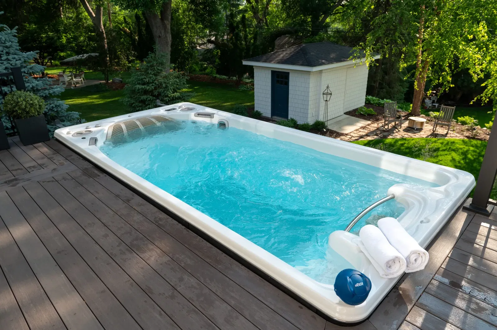 An overhead shot of a swim spa with FROG @ease sitting on its edge alongside 3 rolled up white towels