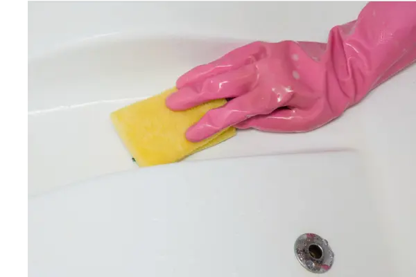 A gloved hand with a sponge wiping the surfaces of a swim spa