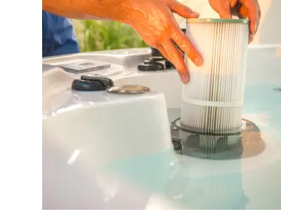 Man's hands pull a filter out of a swim spa's interior.