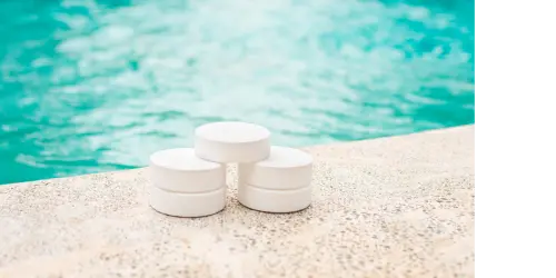 A shot of a pool edge with 3 chlorine pucks stacked in a pyramid.