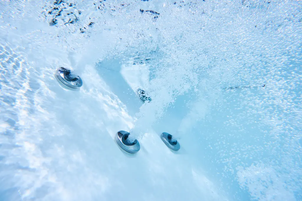 Underwater shot of hot tub jets. The water is slightly cloudy.